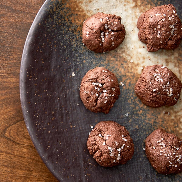 A plate of brown cookies with white crystals on top and salt.