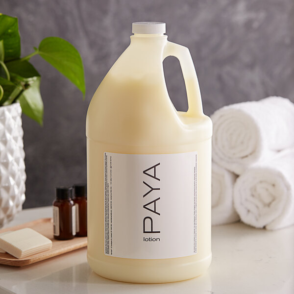 A case of PAYA Papaya lotion jugs on a counter next to towels and a plant.