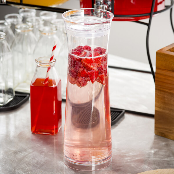 A Tablecraft plastic carafe filled with water and strawberries on a table.