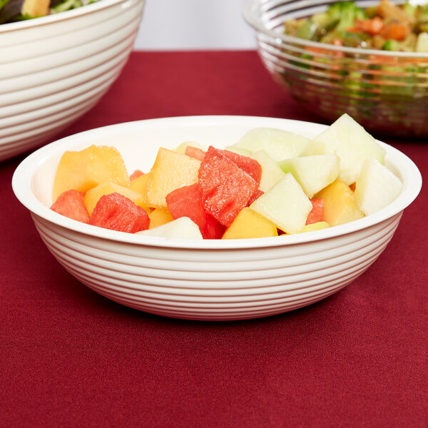A white Cambro round ribbed bowl filled with fruit salad on a table.