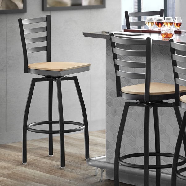 A Lancaster Table & Seating black metal swivel bar stool with a natural wood seat.