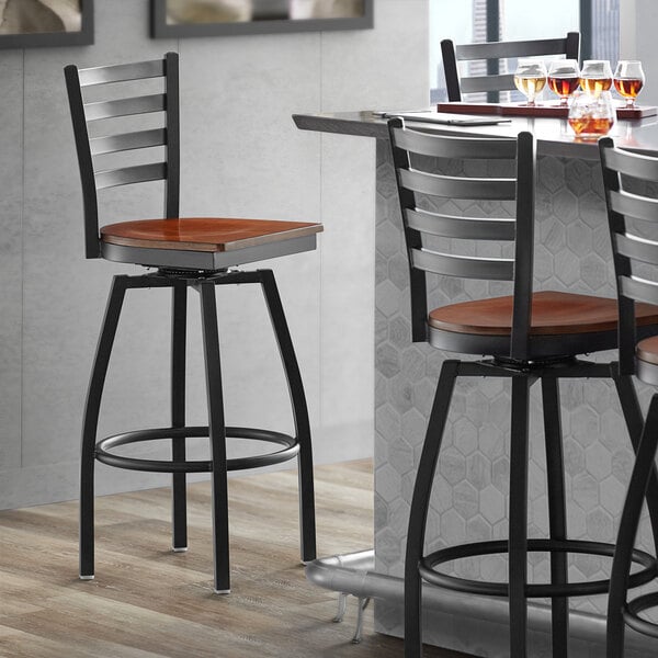 A Lancaster Table & Seating black metal swivel bar stool with a wooden seat.