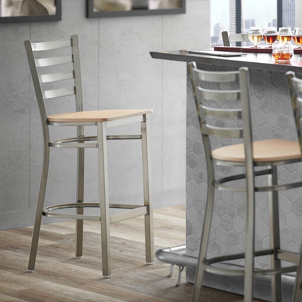 A Lancaster Table & Seating bar stool with a wooden seat and back.