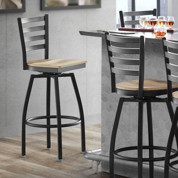A Lancaster Table & Seating black swivel bar stool with a driftwood seat.