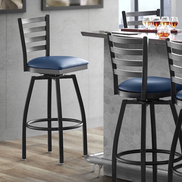 A Lancaster Table & Seating black bar stool with a navy blue padded seat and backrest.