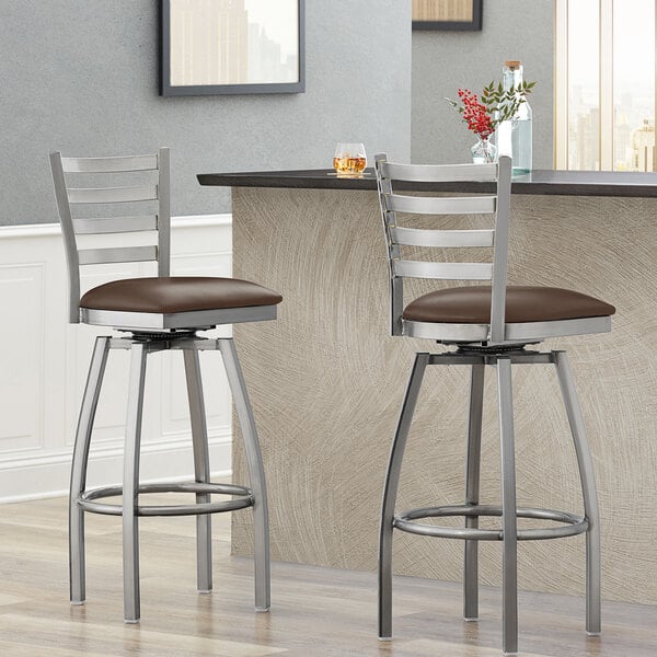 Two Lancaster Table & Seating ladder back bar stools with dark brown padded seats.