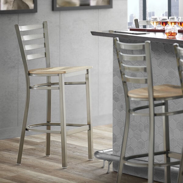 A Lancaster Table & Seating clear coat finish ladder back bar stool with a driftwood seat and metal frame.