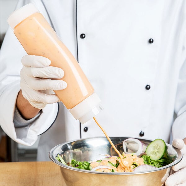 A chef pouring sauce into a bowl using a Tablecraft Dualway squeeze bottle.