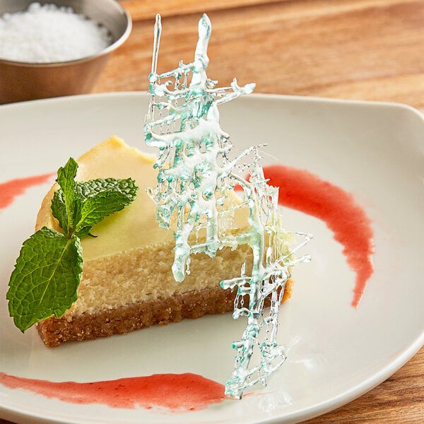 A piece of cheesecake with a mint leaf on a plate.