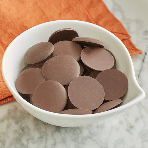 A bowl of Guittard Soleil d'Or milk chocolate wafers.