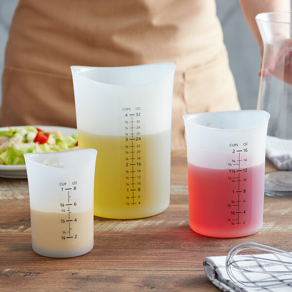 A woman uses an iSi translucent measuring cup to measure red liquid.