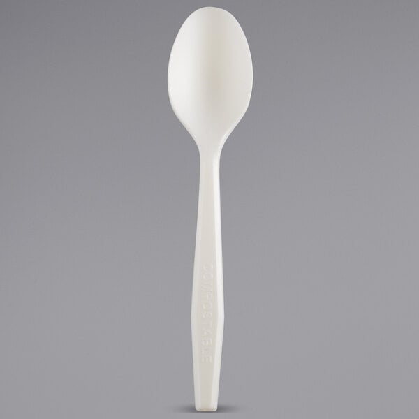 A white Fineline plastic spoon on a gray surface.