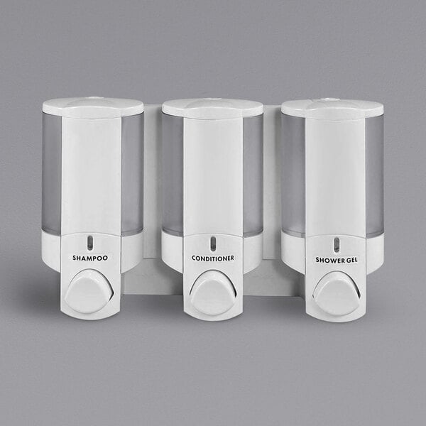 Three white Dispenser Amenities Aviva soap dispensers on a wall.