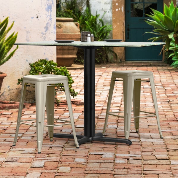 A Lancaster Table with a white base and a plate on top on a brick patio.