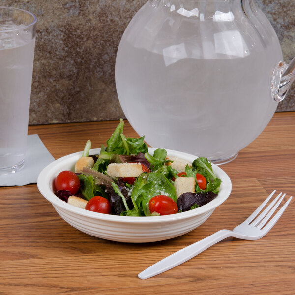 A bowl of salad in a white Cambro ribbed bowl with a fork on a counter.