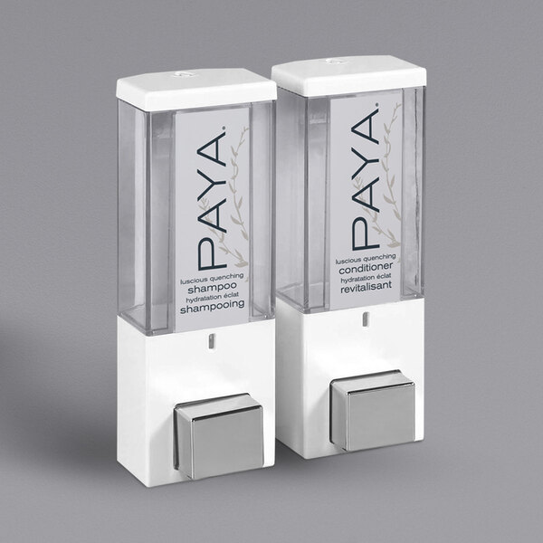 A white wall-mounted Dispenser Amenities shower dispenser with two translucent bottles of Paya shampoo.