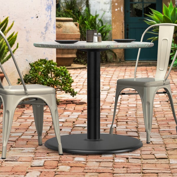 A Lancaster Table & Seating black table base with chairs on a brick patio.