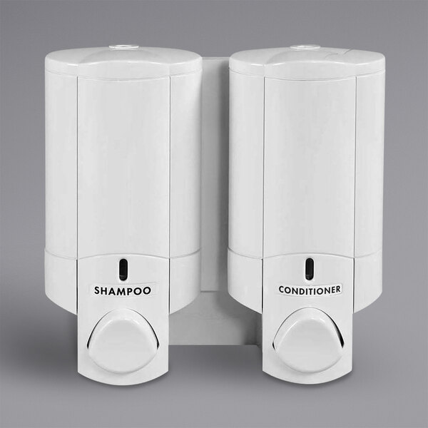 A white Dispenser Amenities wall mounted shower dispenser with two chambers and bottles.