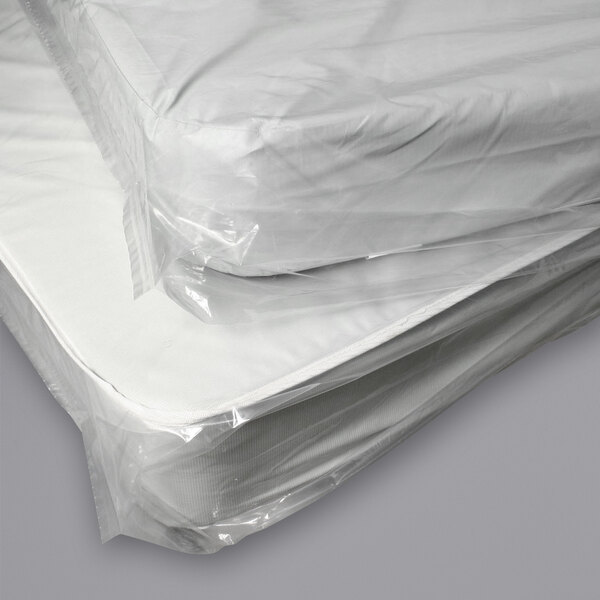 A stack of two twin mattresses in LK Packaging plastic bags with vent holes.
