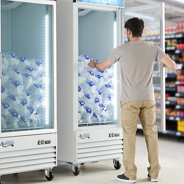 An Avantco white glass door ice merchandiser filled with bags of ice.