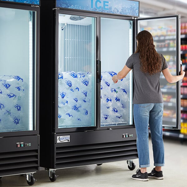 A woman standing in front of an Avantco ice merchandiser with a customizable panel.