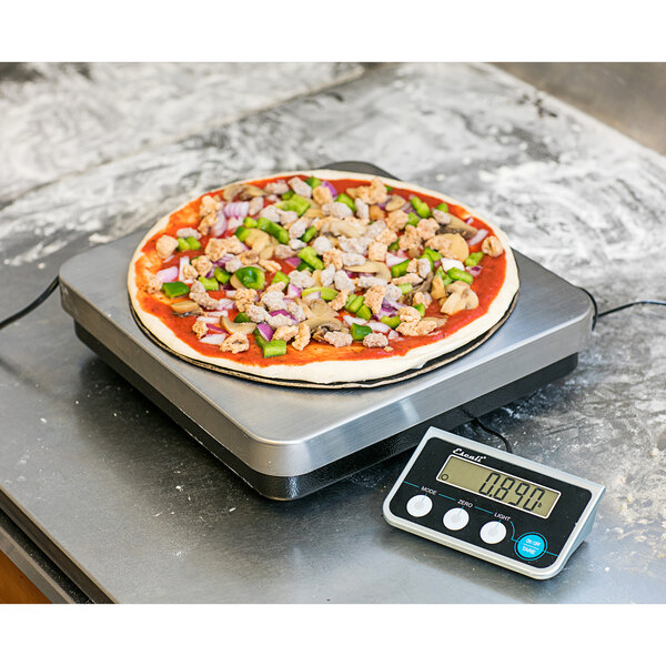 A pizza with toppings on a black San Jamar digital portion scale.