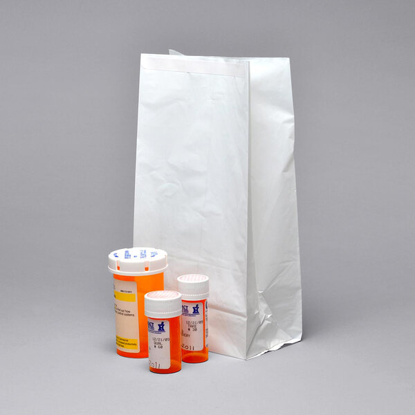 A white LK Packaging pharmacy bag with a bottle and a container of pills.