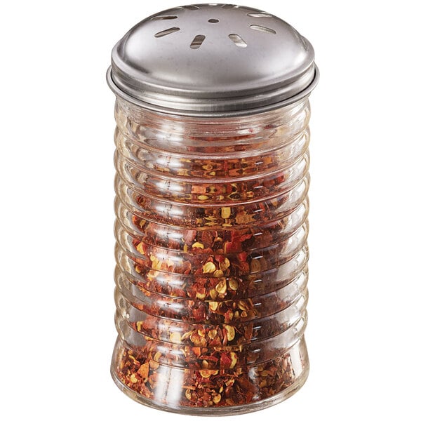 An American Metalcraft glass beehive spice shaker with a stainless steel lid filled with red pepper flakes.