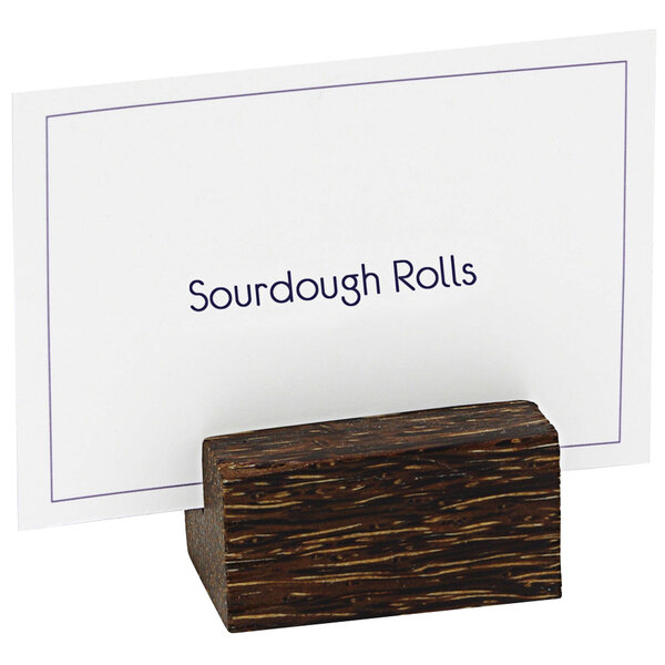 A Front of the House palm wood table card holder with a white card in it.