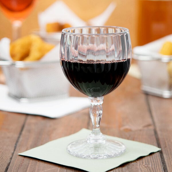 A customizable fluted wine glass filled with red wine on a table.