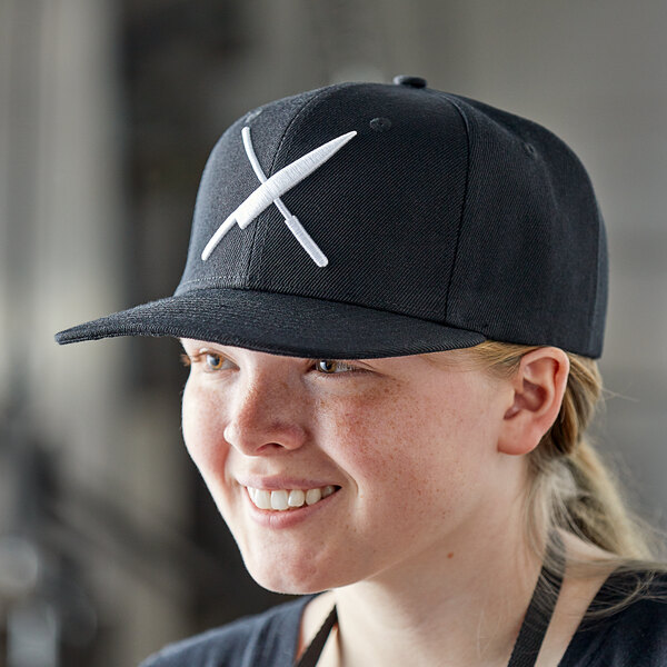 A woman wearing a black Mercer Culinary hat with a large white logo.