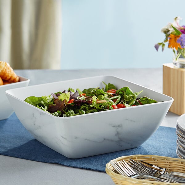 An American Metalcraft white marble square melamine bowl filled with salad on a table.