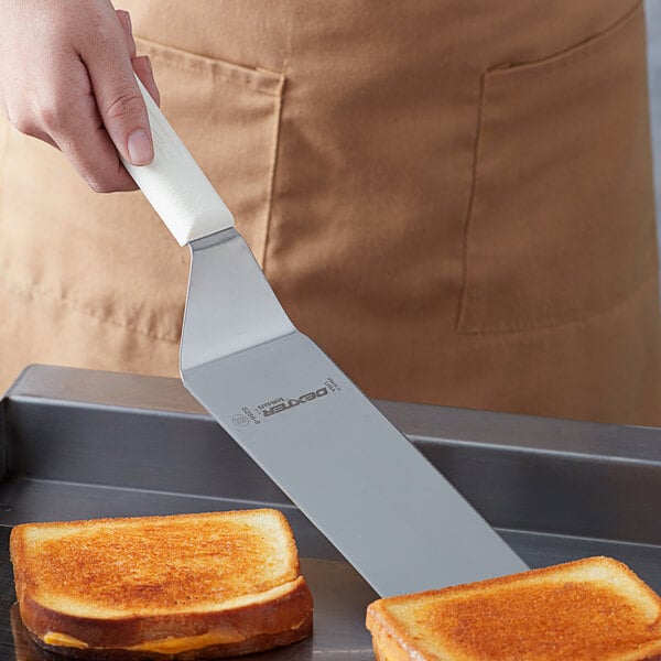A person using a Dexter-Russell Sani-Safe solid turner to lift toast from a counter.