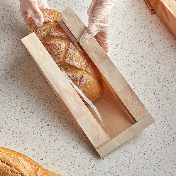 A person in gloves holding a loaf of bread in a Bagcraft Packaging EcoCraft Dubl-Panel Artisan Bread Bag.