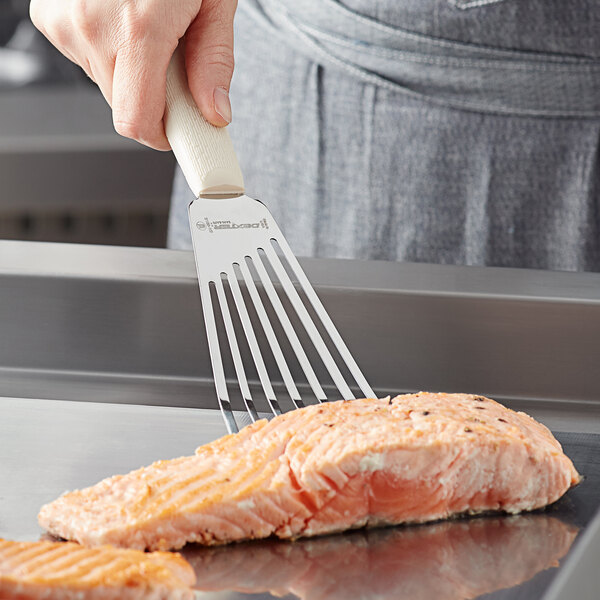 A person using a Dexter-Russell slotted fish turner to lift cooked salmon