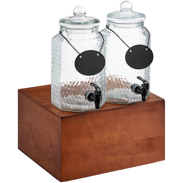 Two Acopa glass jars with black labels on a wooden stand.