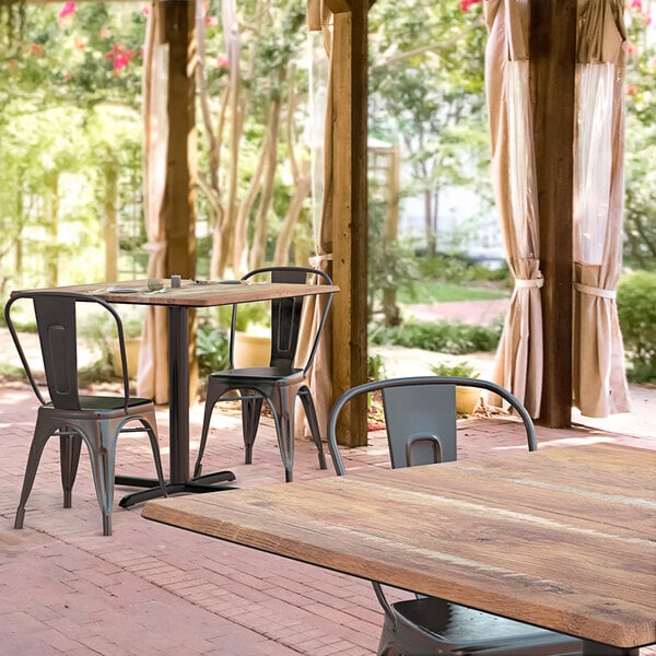 A Lancaster Table & Seating Excalibur table and chairs on an outdoor brick patio.