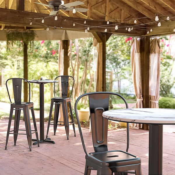 A Lancaster Table & Seating round bar height table with a cross base on a patio.