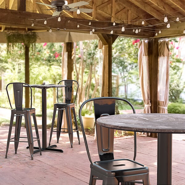 A Lancaster Table & Seating Excalibur bar height table with chairs on a covered patio.