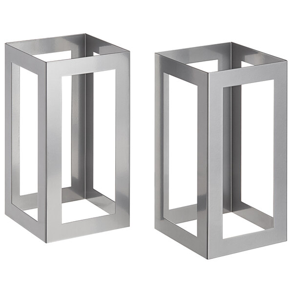 Two square stainless steel risers on a metal table.