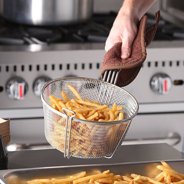 A person holding a Carlisle round chrome-plated steel fryer basket of french fries.