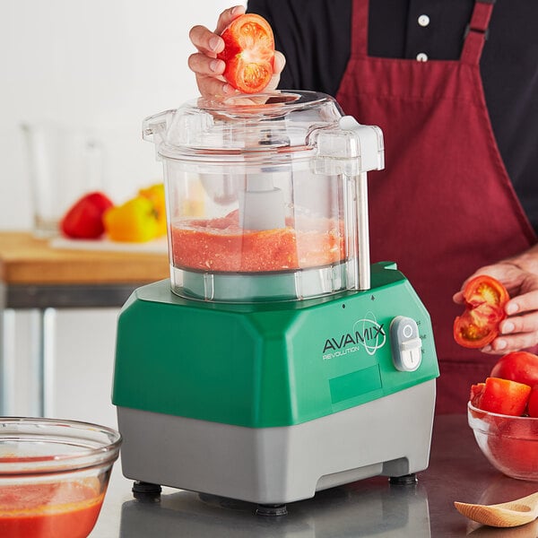 A person using an AvaMix food processor to juice tomatoes.