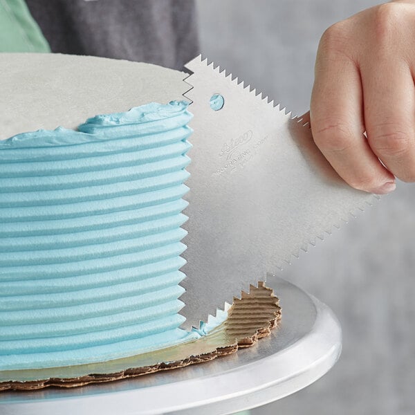 A person using an Ateco icing comb to decorate a cake.