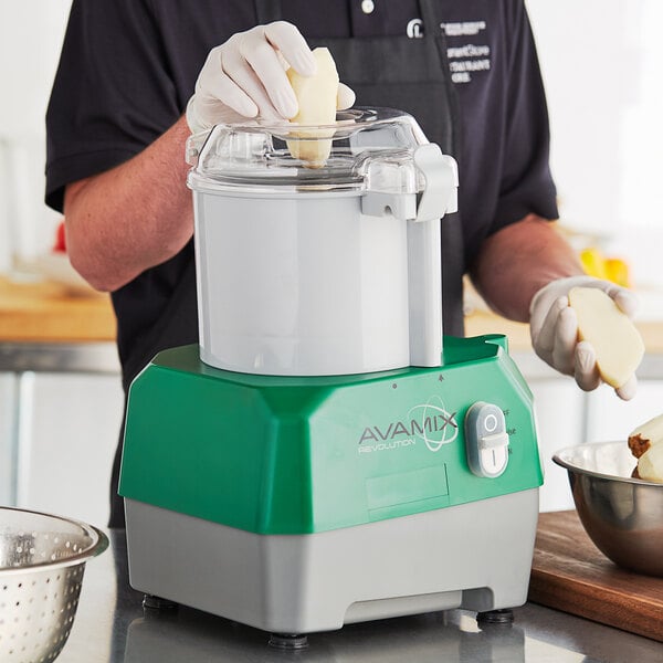 A person using an AvaMix gray food processor to make food.