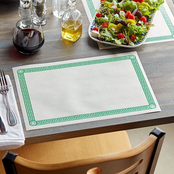 A table set with a green Greek key placemat, a fork, and a plate of salad.
