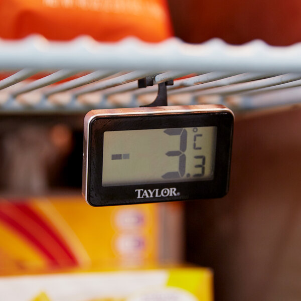 A Taylor digital thermometer on a shelf in a refrigerator.