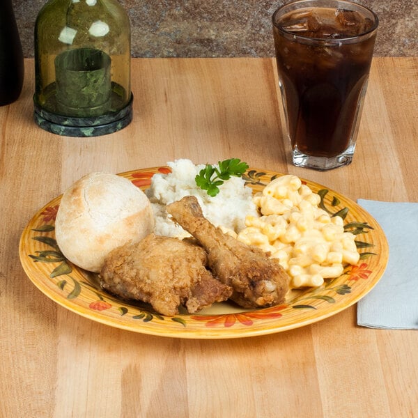 A Venetian wide rim plate with fried chicken, mashed potatoes, and corn on the cob with a drink on the table.
