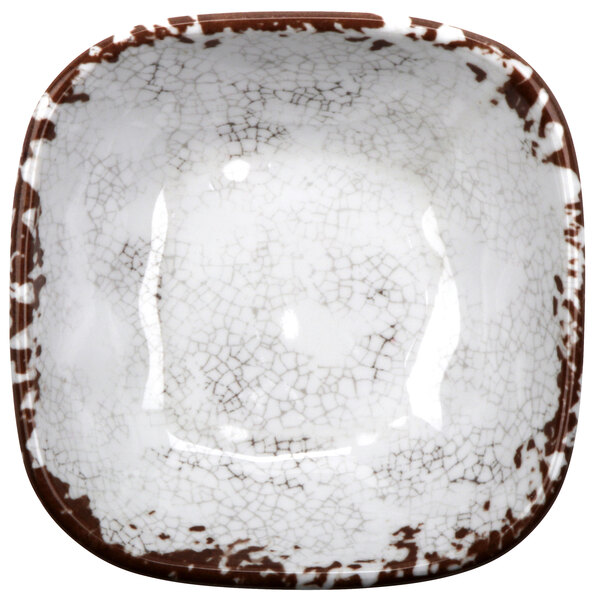 A close-up of a white square melamine bowl with brown and white speckles.