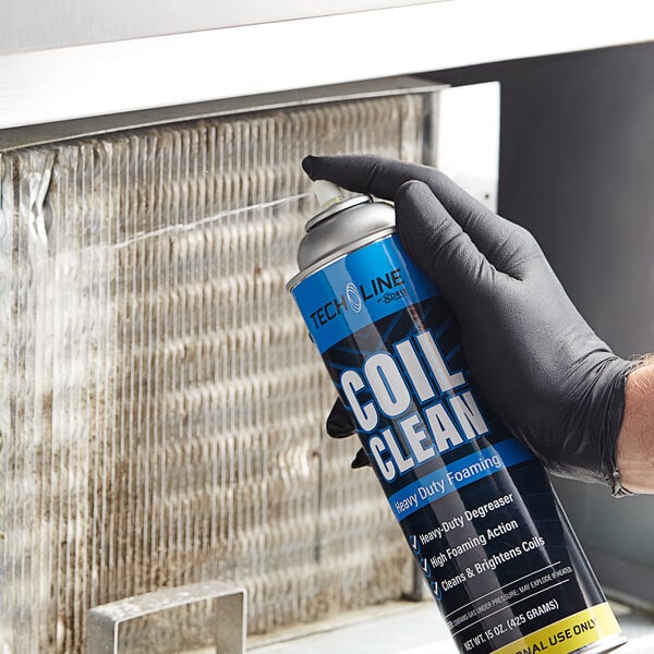A person in gloves spraying a metal surface with a blue can of Noble Chemical Tech Line heavy-duty foam.