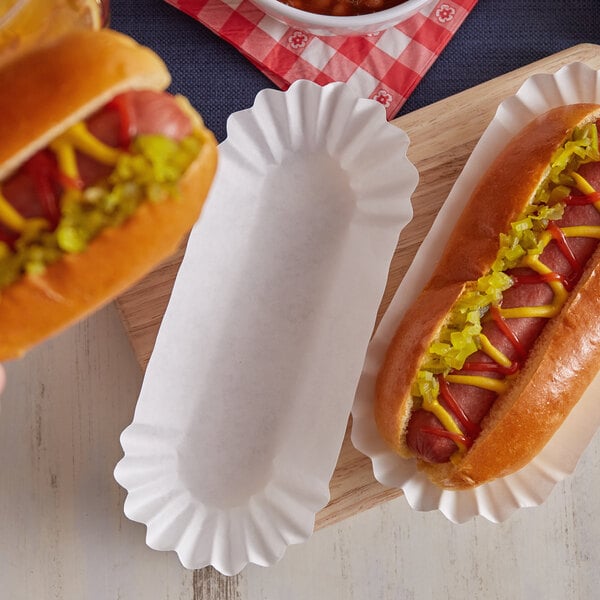 Two hot dogs served in white paper fluted trays with mustard and ketchup.